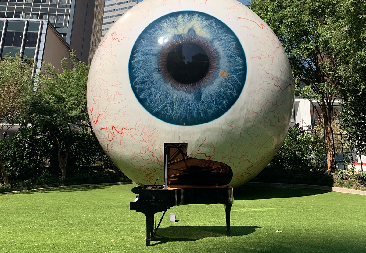 a piano in front of a sculpture of a giant eyeball