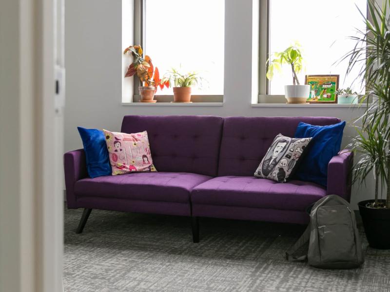 An small conference room windows and a purple couch with cushions