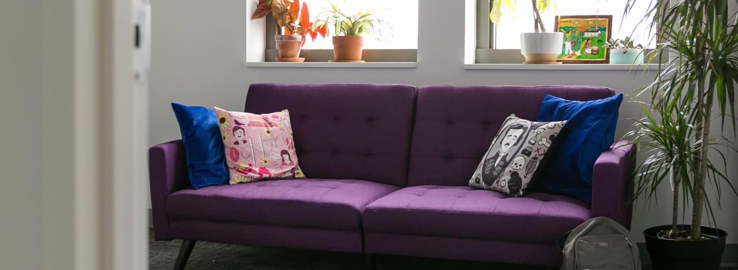 An small conference room windows and a purple couch with cushions