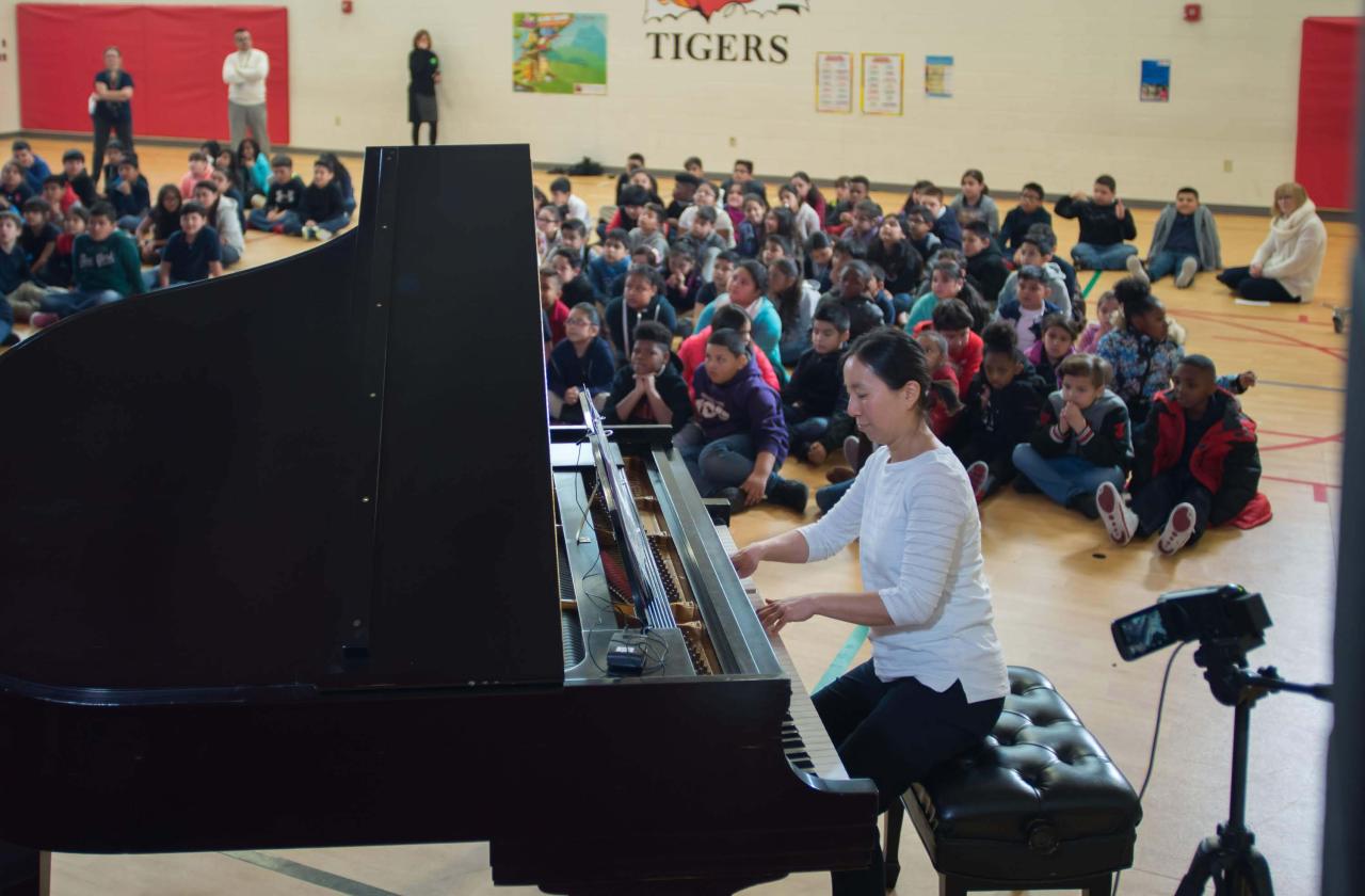 Children watch a host and pianist at a Cliburn in the Classroom program